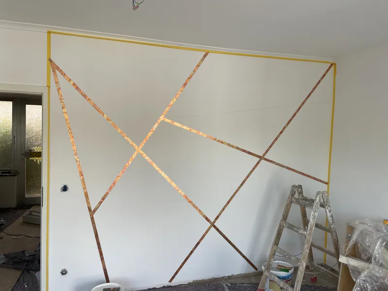 Wandgestaltung mit grafischem Linienmuster in Kupfer, während der Ausführung
