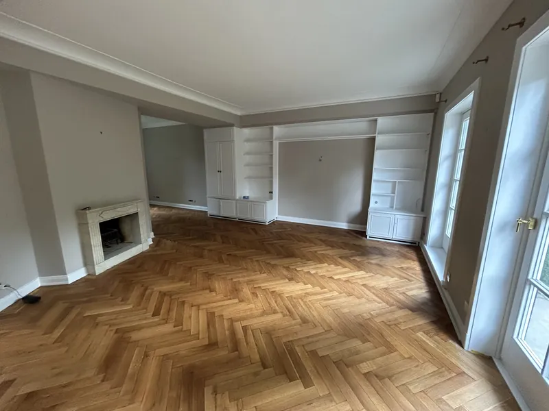 Altbauzimmer mit Fischgrätparkett, Kamin und hellen Wänden