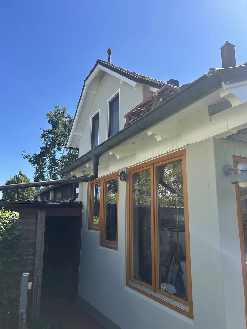 Einfamilienhaus mit hellem Fassadenanstrich und Holzfenstern