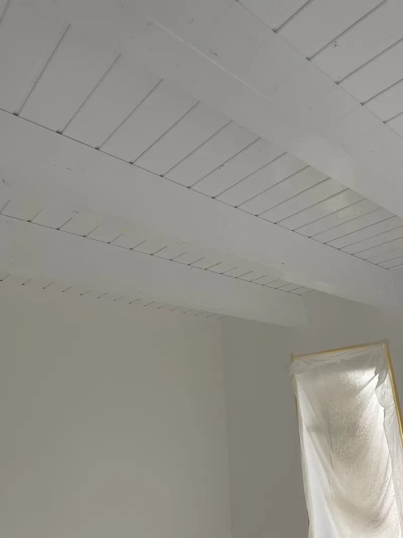Dieselbe Decke nach dem weißen Anstrich, Balken und Bretter deckend gestrichen