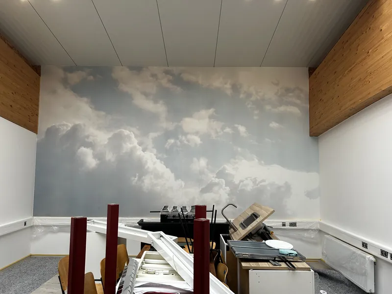 Wandbild mit Wolkenmotiv neben einer Holzverkleidung