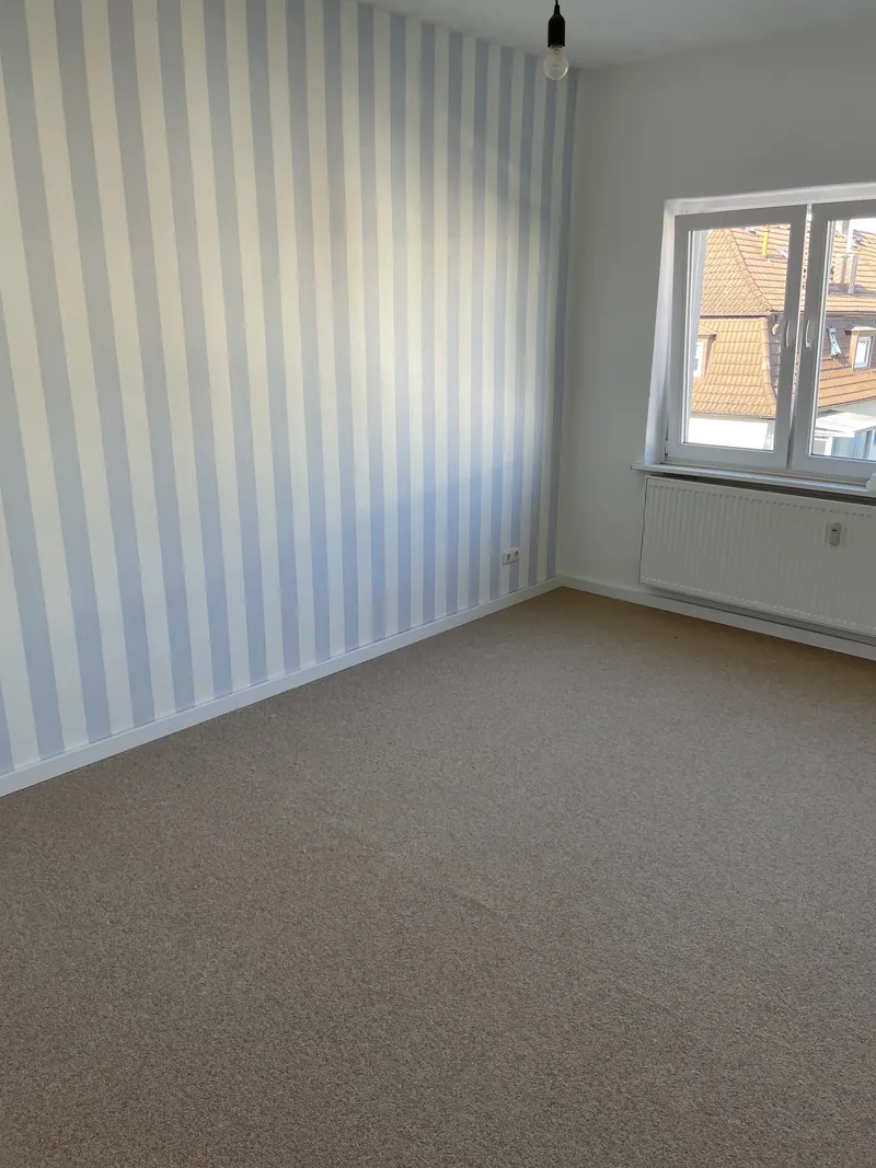 Zimmer mit hellblau gestreifter Tapete und Teppichboden