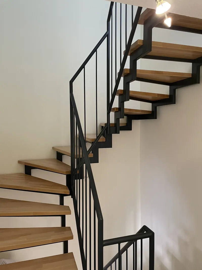 Dieselbe Treppe fertig, schwarze Stahlwangen mit hellen Holzstufen