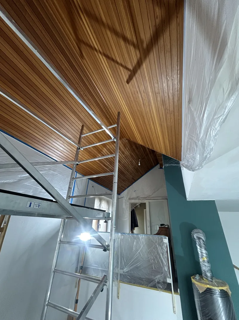 Holzdecke und petrolfarbene Wand in einem Raum mit Gerüst
